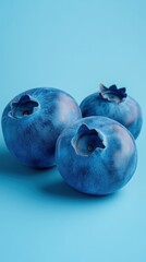 Obraz premium Three fresh blueberries close up studio shot on blue background healthy eating concept minimalist style vibrant color