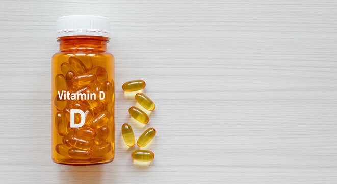 Amber Vitamin D Supplement Bottle with Capsules on Light Wood