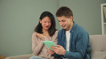 A joyful couple sharing a delightful moment while interacting with a tablet, expressing excitement and engagement as they explore content together in their cozy home atmosphere.