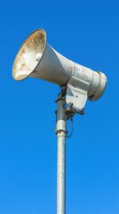 Weathered Megaphone on Pole Against Blue Sky in Vertical Composition; Public Address System Loudspeaker for Announcements and Warnings