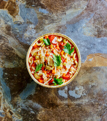 minestrone soup with macaroni, carrot, onion, celery, and crushed tomatoes topped with parsley
