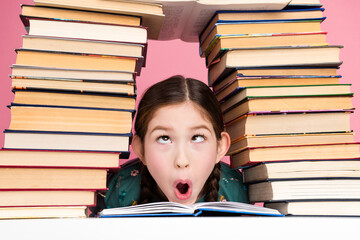 Young girl making a surprised expression with stacked book and colorful background conveying...