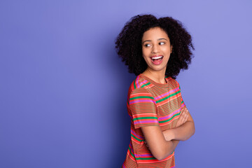 Smiling young woman in a vibrant casual outfit against a purple background, expressing happiness...