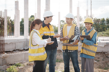 A team of engineers wearing hard hats inspect construction and inspect the site to ensure quality...