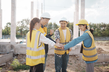 A team of engineers wearing hard hats inspect construction and inspect the site to ensure quality...