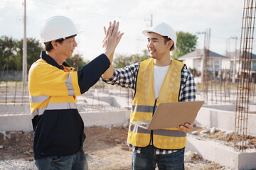 A team of engineers wearing hard hats inspect construction and inspect the site to ensure quality...