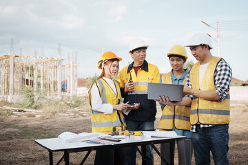 A team of engineers wearing hard hats inspect construction and inspect the site to ensure quality...