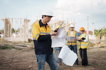 A team of engineers wearing hard hats inspect construction and inspect the site to ensure quality...