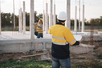 A team of engineers wearing hard hats inspect construction and inspect the site to ensure quality...