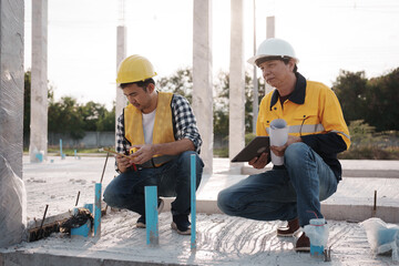 A team of engineers wearing hard hats inspect construction and inspect the site to ensure quality...