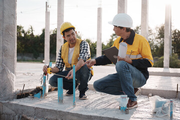 A team of engineers wearing hard hats inspect construction and inspect the site to ensure quality...