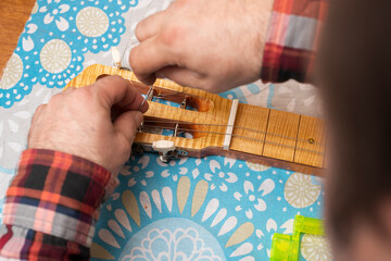 The guitar master inserts the strings on the guitar