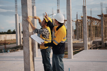 A team of engineers wearing hard hats inspect construction and inspect the site to ensure quality...