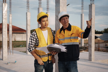 A team of engineers wearing hard hats inspect construction and inspect the site to ensure quality...