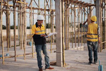 A team of engineers wearing hard hats inspect construction and inspect the site to ensure quality and compliance with design specifications, safety standards and project requirements.