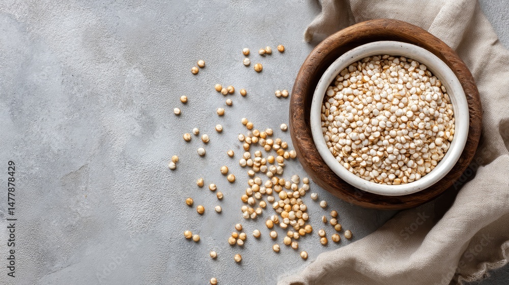 Poster overhead macro shot displays raw quinoa grains in a small white bowl, complemented by a rustic woode