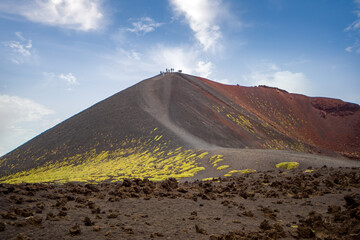 Panoramic view of a volcano crater with tourists at its summit on Mount Etna in Sicily, Italy.