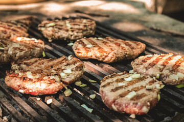 Delicious hamburgers grilling over an outdoor barbecue