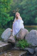 Beautiful girl with long hair and horns in a white dress