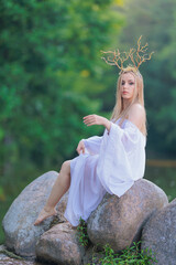 Beautiful girl with long hair and horns in a white dress