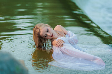 Fototapeta premium Beautiful Girl with long hair swims and dances in water