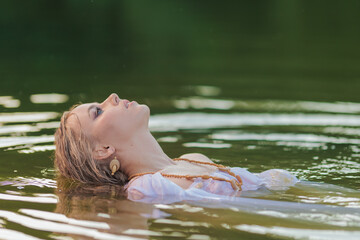 Fototapeta premium Beautiful Girl with long hair swims and dances in water
