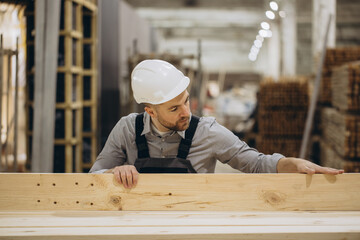 Carpenter inspecting wooden plank in modular building construction