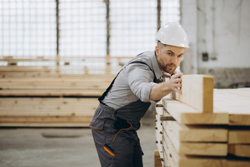 Carpenter checking wooden planks in timber warehouse for modular building industry