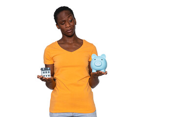 Balancing financial choices with a house model and a piggy bank in hand under bright studio lighting