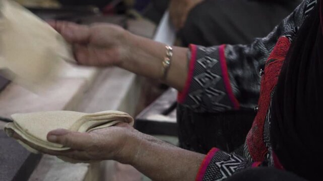 woman folds flatbreads chapati in Delhi Gurdwara Sikh temple common meal