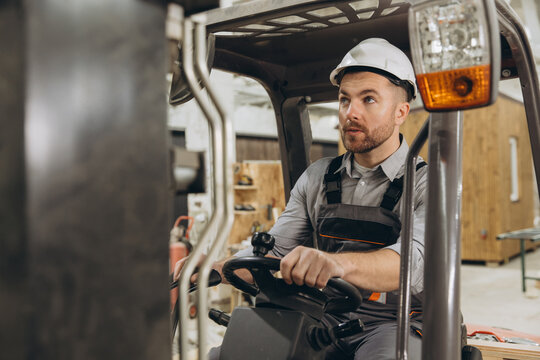 Warehouse worker driving forklift carrying modular building components