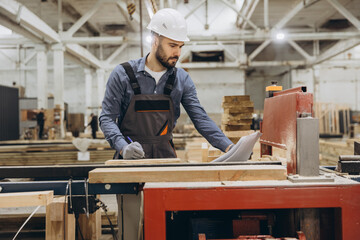 Carpenter working with wood and blueprint in a factory