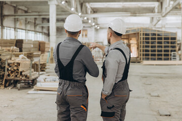 Construction workers discussing prefabricated building project in factory