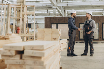 Fototapeta premium Construction workers shaking hands in modular building industry factory