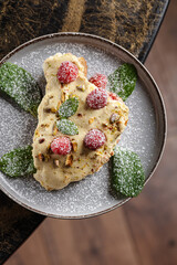 Ricotta Cheesecake with Raspberries & Pistachio. Light ricotta-based cheesecake slice, topped with fresh raspberries, crushed pistachios, powdered sugar, and mint leaves.
