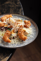 Shrimp Caesar Salad – Classic Caesar salad topped with crispy breaded shrimp, fresh romaine lettuce, cherry tomatoes, croutons, and grated parmesan, served with Caesar dressing.