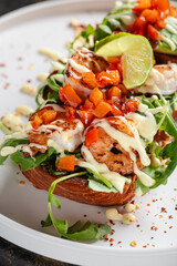 Open Chicken Sandwich with Avocado & Chickpeas – Toasted bread topped with grilled chicken breast, fresh arugula, avocado slices, roasted chickpeas, tomato salsa, and creamy dressing.