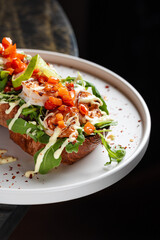 Open Chicken Sandwich with Avocado & Chickpeas – Toasted bread topped with grilled chicken breast, fresh arugula, avocado slices, roasted chickpeas, tomato salsa, and creamy dressing.