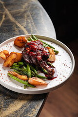 Duck Leg with Berry Sauce – Tender roasted duck leg topped with rich berry reduction, served with golden baby potatoes and sautéed green beans.
