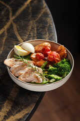 Grilled Chicken Bowl with Vegetables – A wholesome bowl with grilled chicken breast, roasted cherry tomatoes, baby potatoes, tender broccoli, asparagus, and a soft-boiled egg, garnished with rosemary.