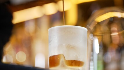 Closeup bartender pouring mixed cocktail whiskey into cool glass textured cooling ice drink making special advertisement creative focusing alcohol refresh showcase at warm light nightclub. Vinosity.