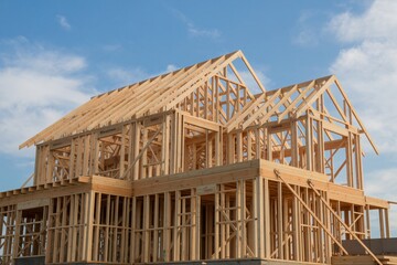 Wooden Frame of a New House Under Construction Against a Sky with Light Clouds