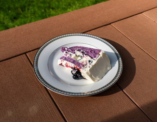 A slice of blueberry cake on a white plate on a wooden surface 