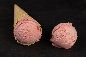 cold pink ice cream with strawberry flavor, ice cream in a waffle cone, close up