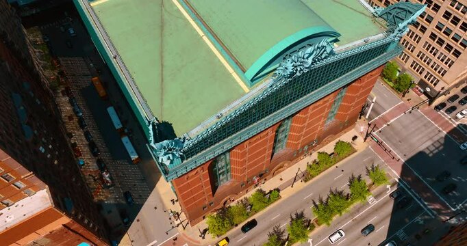 Rising over the green roof of Harold Washington Library. Many cars go by the roads near the building. Top view. Chicago, Illinois, USA.
