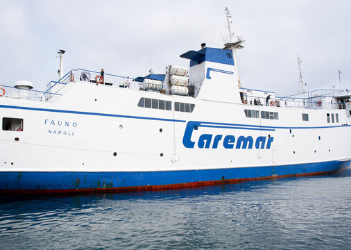 Caremar ferry named Fauno docked in Napoli, showcasing its blue and white exterior against a cloudy sky, representing maritime transportation and travel experiences