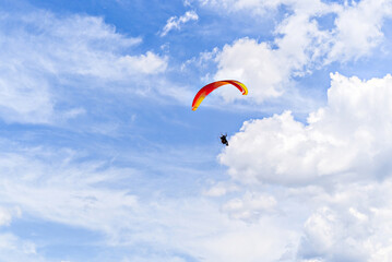 Paragliding adventure with a red and blue parachute on a sunny day.