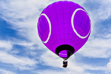 Colorful hot air balloon flying over blue sky with white clouds	