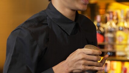 Closeup Asian hand bartender shaking mixed cocktail at luxurious counter preparation for making special drink menu for VIP guest at fronted bar. Special refresh drink showcasing nightlife. Vinosity.