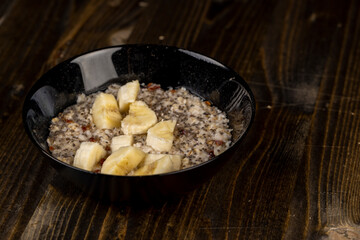 banana in porridge, boiled oatmeal porridge with chia seeds, berries and banana, close up, side view